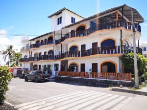 Un grand bâtiment blanc avec balcon se trouve dans une rue. dans l'établissement Hostal Sandrita, à Puerto Villamil