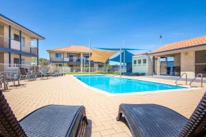 a swimming pool with two chairs in front of a building at Pinnacles Edge Resort in Cervantes