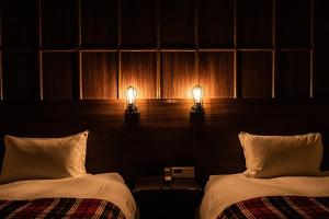 two beds in a room with two lights on them at THE STEEL HOUSE in Kitakyushu