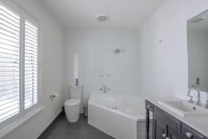 a white bathroom with a tub and a toilet and a sink at Mark and Kate's Place in Bendigo