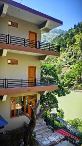 本贾尔Tirthan Grand Riverside的前面有一棵树的建筑物