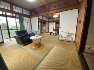 ein Wohnzimmer mit einem schwarzen Sessel und einem Tisch in der Unterkunft てぃだかんかん Tida-kan-kan -SEVEN HOTELS & Resorts- in Motobu