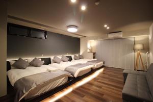 a room with three beds and a couch in it at Precioso Umeda Central Osaka - Self Check-In Only in Osaka