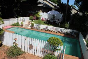 a swimming pool next to a white fence with a table at Mia's in Tzaneen