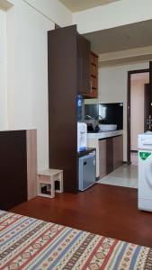 a kitchen with a refrigerator, stove, microwave and a bed at Apartemen The Suites Kayla in Bandung