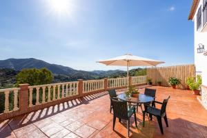 un patio con mesa, sillas y sombrilla en Casa Mari en Almogía