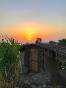 uma pequena cabana com o pôr-do-sol ao fundo em suite truck- Natura Eco farm em Natur
