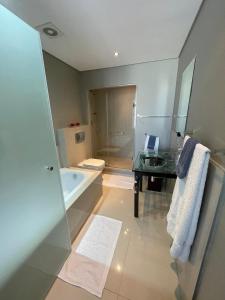 a bathroom with a tub and a toilet and a sink at Infinity Self Catering Beachfront Apartment 302 in Cape Town