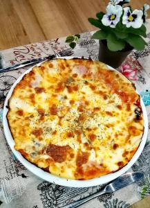 a cheese pizza in a white plate on a table at Hotel Brilliantin in Sliven