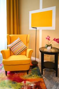 ein Wohnzimmer mit einem gelben Stuhl und einem Tisch in der Unterkunft Highlight Suite Donaustadt in Wien