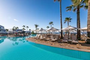 アヤナパにあるAtlantica SunGarden Beachのラウンジチェアとパラソル付きのスイミングプール