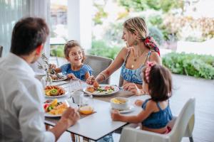 una familia sentada en una mesa comiendo comida en Sofianna Resort & Spa en Pafos