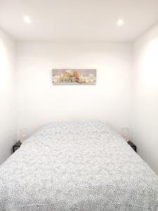 a white bedroom with a bed and a picture on the wall at Cosy Paris CDG Stade de France in Le Blanc-Mesnil