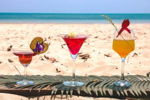 four cocktails sitting on a table on the beach at Munjoh Ocean Resort - Private Beachfront Luxury Retreat in Havelock in Havelock Island