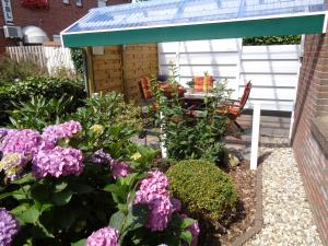 einen Garten mit einem Tisch und lila Blumen in der Unterkunft Bastan - Haus Katharina in Emden