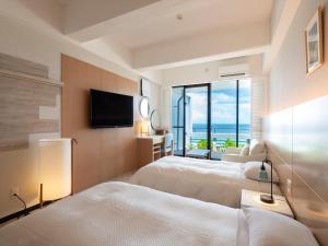恩納村にあるパレスインムーンビーチのベッド2台、薄型テレビが備わるホテルルームです。