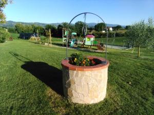 un gran plantador de piedra en un patio con parque infantil en Agriturismo Consalvi Valentina, en Marsciano