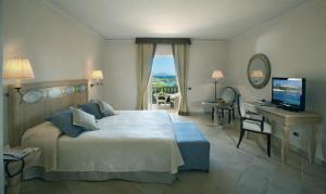 een slaapkamer met een bed, een bureau en een televisie bij Petra Bianca in Porto Cervo