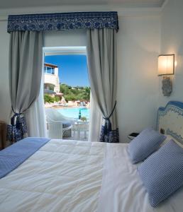 a bedroom with a bed and a view of a pool at Petra Bianca in Porto Cervo