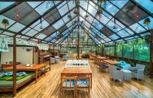 a conservatory with a glass ceiling and tables and chairs at Munjoh Ocean Resort - Private Beachfront Luxury Retreat in Havelock in Havelock Island