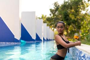 a woman holding a glass of wine next to a swimming pool at Munjoh Ocean Resort - Private Beachfront Luxury Retreat in Havelock in Havelock Island