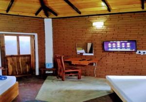 a room with a desk and a tv on a brick wall at Rice Rice Villas in Tissamaharama