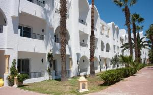 eine Reihe weißer Wohnhäuser mit Palmen in der Unterkunft Hotel Nesrine Hammamet in Hammamet