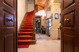 un couloir avec un escalier de moquette rouge dans une maison dans l'établissement Palazzino Di Corina, à Réthymnon