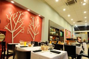 a restaurant with white tables and chairs and a red wall at Hotel Osam in Buenos Aires