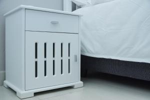 a white cabinet next to a bed in a room at Greyville Apartments in Lusaka