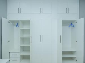 a white closet with white cabinets and blue handles at Greyville Apartments in Lusaka