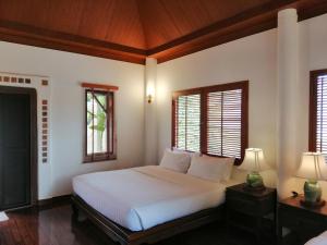 a bedroom with a white bed and two windows at Casa Khaoyai Bed&Breakfast in Mu Si