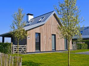 a wooden house with a gambrel roof at Holiday Home Oesterdam Resort by Interhome in Tholen