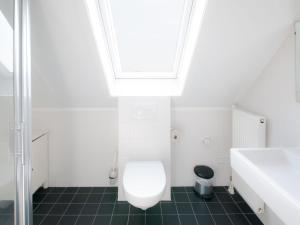 a white bathroom with a toilet and a sink at Holiday Home Oesterdam Resort-5 in Tholen