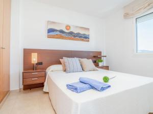 a bedroom with a white bed with two blue towels on it at Apartment Nuvol Blau-3 by Interhome in Roses