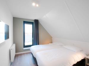 a white bed in a room with a window at Holiday Home Oesterdam Resort-1 in Tholen