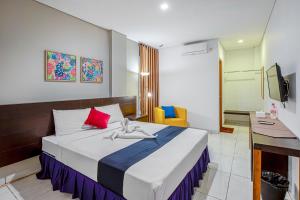 Dormitorio con cama, escritorio y TV en Sans Hotel Prime Cailendra Yogyakarta by RedDoorz en Yogyakarta