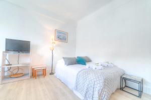 um quarto branco com uma cama e uma televisão em IMMOGROOM - Appartment - 1min from the beach - Wifi em Cannes