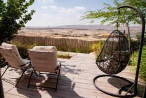 eine Terrasse mit 2 Stühlen und einem Netz in der Unterkunft Desert View in Jerocham