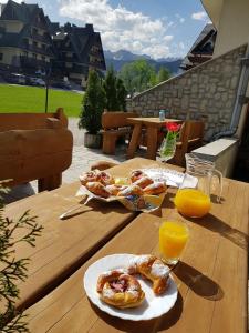 una mesa de madera con 2 platos de bollería y zumo de naranja en Chata pod Jemiołą, en Zakopane