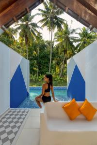 a woman sitting on a couch in front of a pool at Munjoh Ocean Resort - Private Beachfront Luxury Retreat in Havelock in Havelock Island