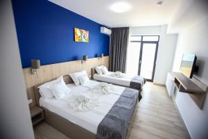 Habitación de hotel con 2 camas y pared azul en Vila Panoramic, en Eforie Nord