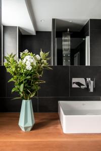 a bathroom with a white sink and a vase with flowers at Mozart Apartment München in Munich