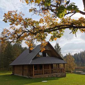 a log cabin with a black roof in a field at Leimaņi in Vaidava