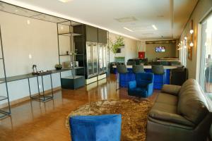 a lobby with a couch and blue chairs and a counter at ONE HOTEL in Ituiutaba