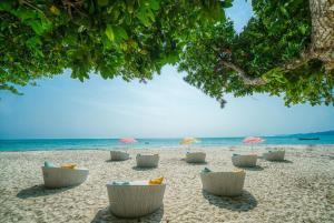 a beach with chairs and umbrellas and the ocean at Munjoh Ocean Resort - Private Beachfront Luxury Retreat in Havelock in Havelock Island