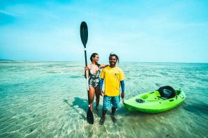 a man and woman standing in the water next to a kayak at Munjoh Ocean Resort - Private Beachfront Luxury Retreat in Havelock in Havelock Island