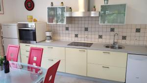 a kitchen with white cabinets and a sink and red chairs at Apartment Coraline on Korcula, seafront in Smokvica