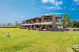 una casa grande con un campo de hierba delante de ella en Terra d'Oro Villas en Ierissos