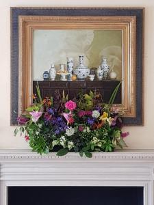 a framed picture of flowers on top of a fireplace at Old Church Farm in Rudgeway